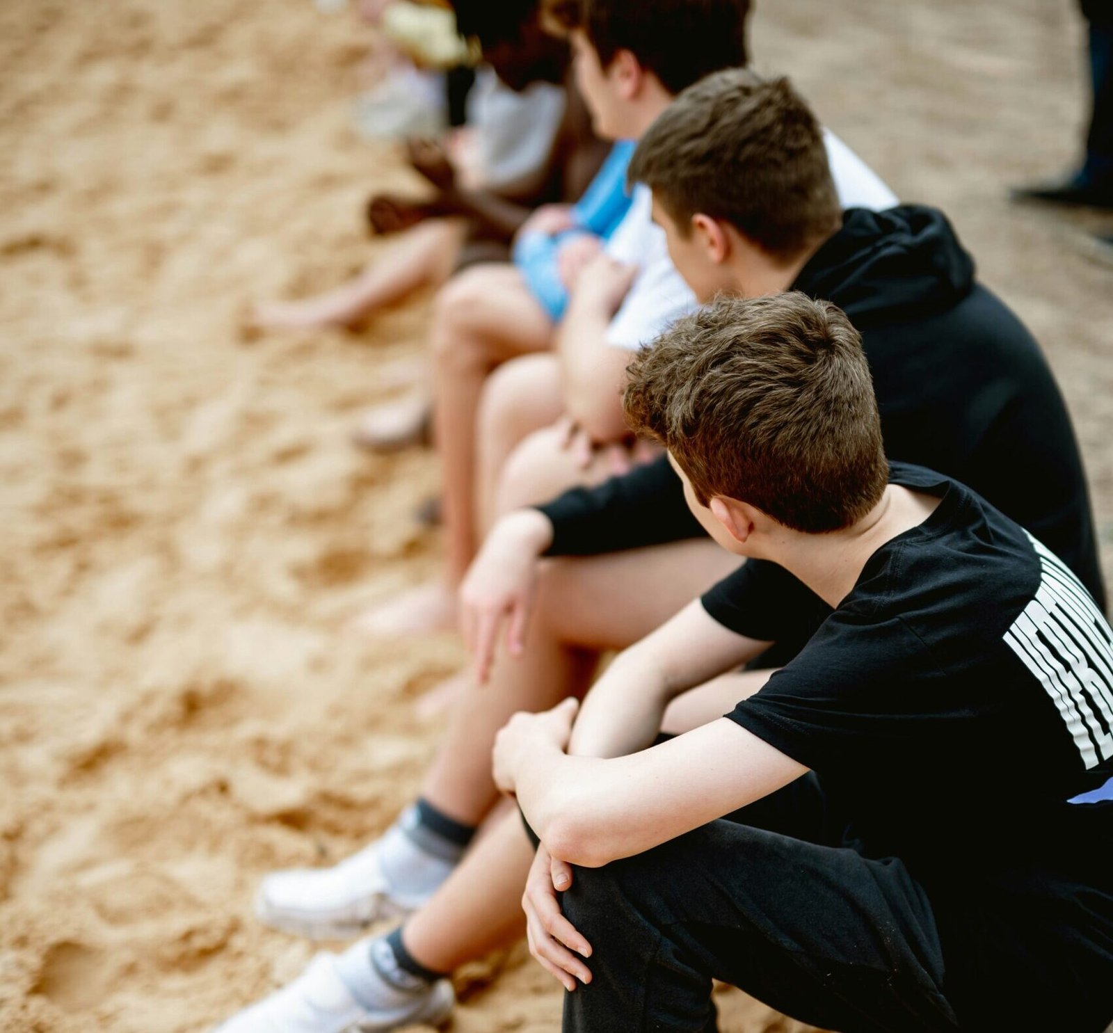 Image of kids sitting in a row on a beach